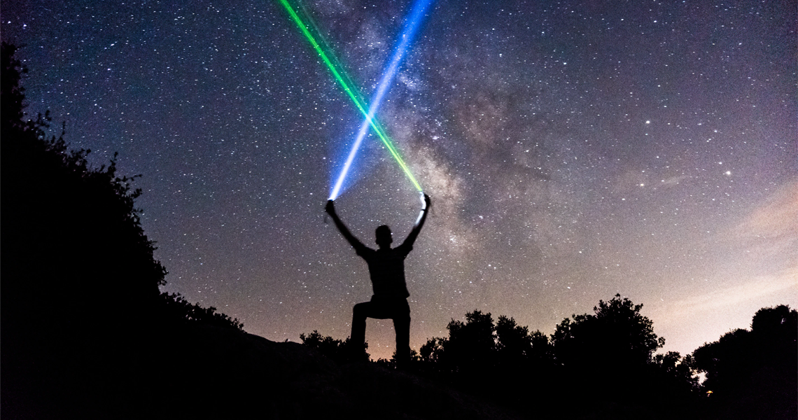 night sky with silhouette of person holding a light saber